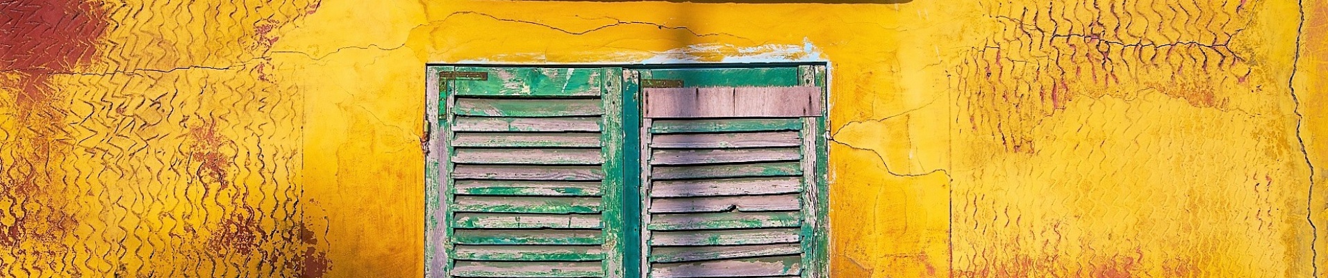 vieille fenêtre verte sur une façade jaune et rouge dans la ville de Saint-Louis, au Sénégal