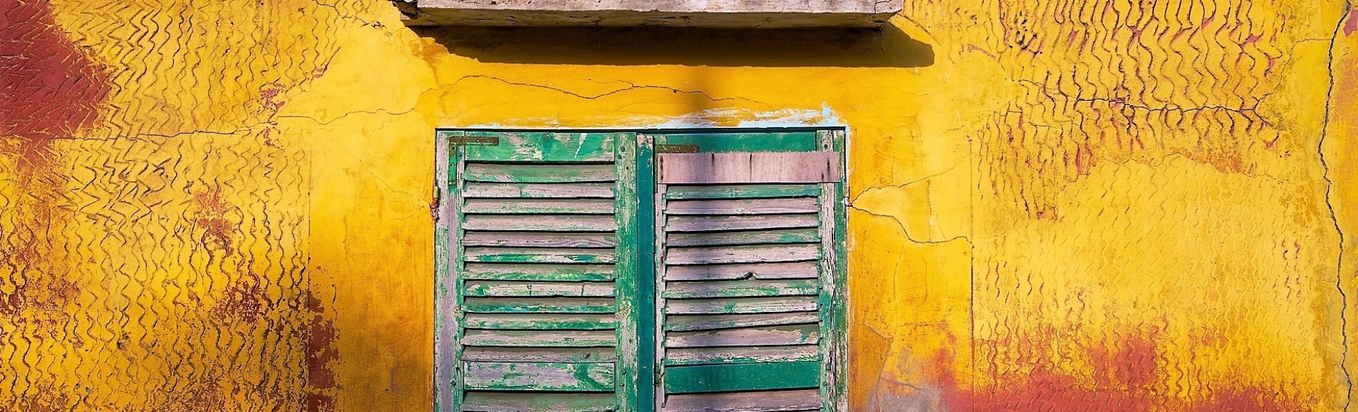 vieille fenêtre verte sur une façade jaune et rouge dans la ville de Saint-Louis, au Sénégal