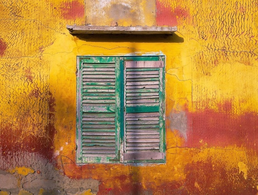 vieille fenêtre verte sur une façade jaune et rouge dans la ville de Saint-Louis, au Sénégal