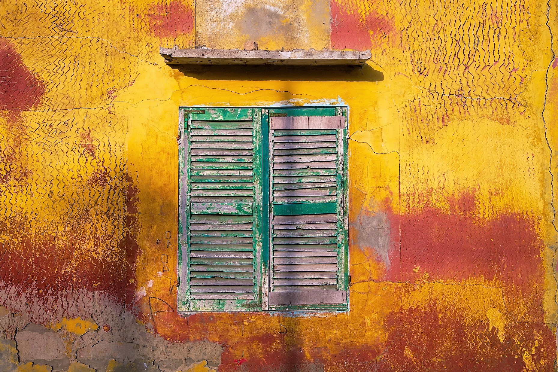 vieille fenêtre verte sur une façade jaune et rouge dans la ville de Saint-Louis, au Sénégal