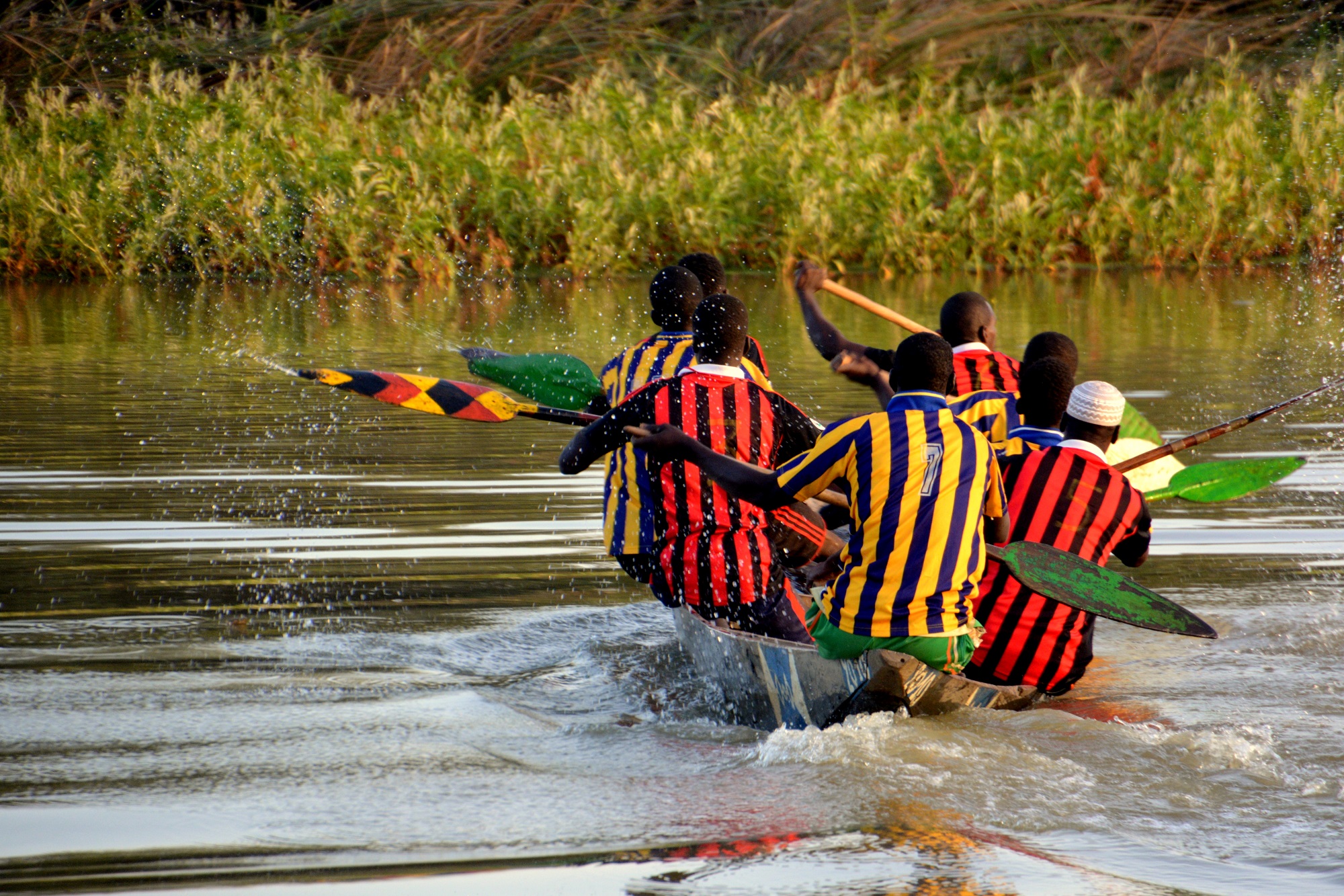 sénégalais sur une pirogue avec des maillots de sport en train de ramer