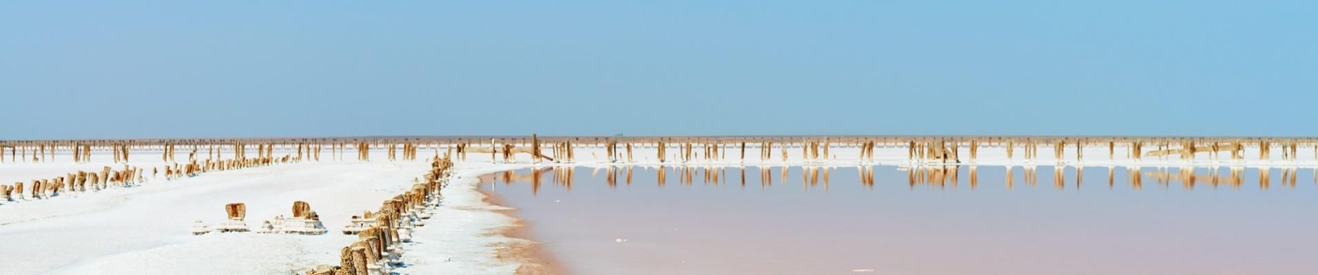 Poteaux de bois enfoncés dans le sable au Lac Retba